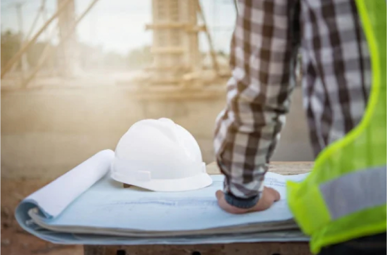 construction worker on site looking at plans with his hard hat on the table