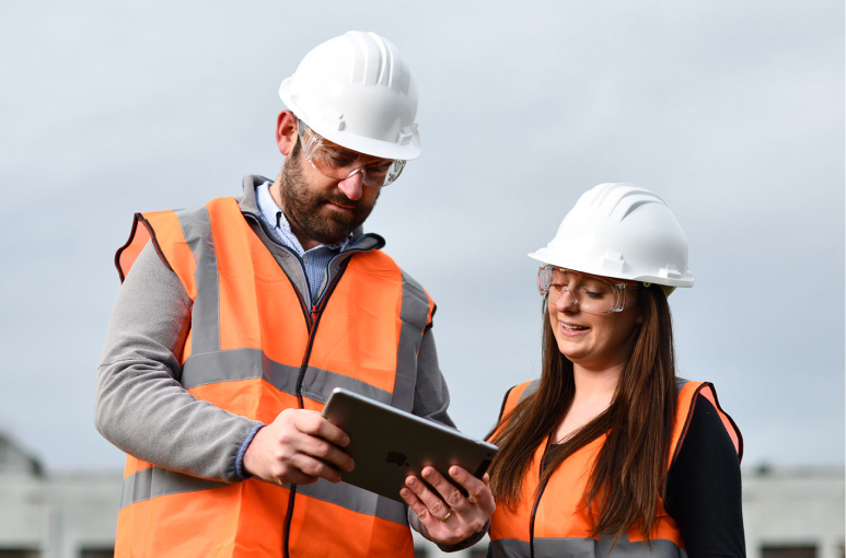 two construction workers looking at an ipad at msite dashboards